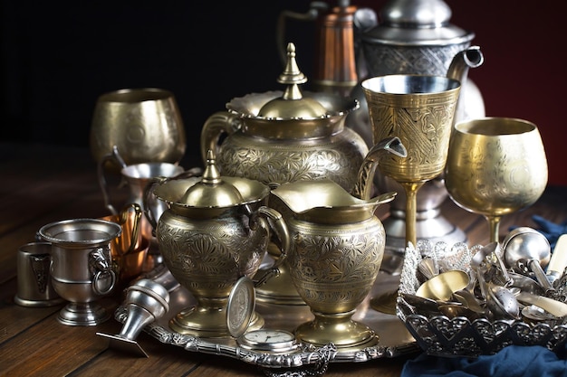 A collection of vintage brass cups and a silver tray with a silver cup on it.