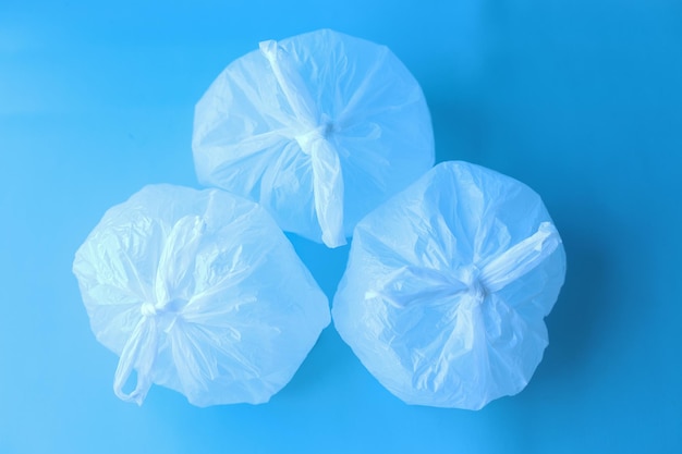 Collection of white disposable plastic bags on blue background.