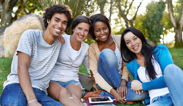 College diversity Shot of a diverse group of college students sitting outside using digital tablet