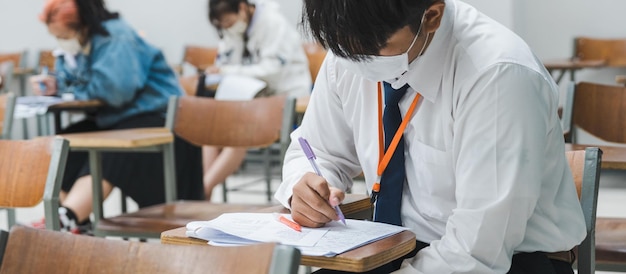 College students writing on final examination papers in the classroom concentratively