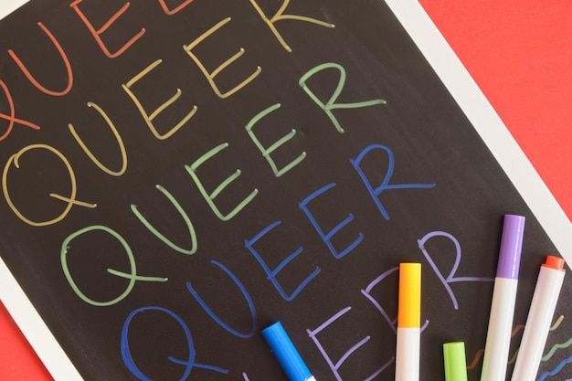 Coloful inscription queer on black board on red background