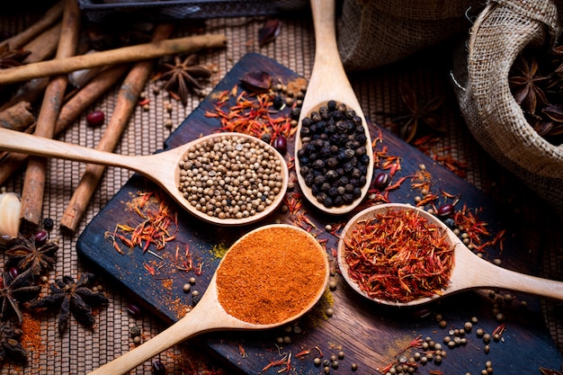 Coloful various spice and herbs in wood spoon on natural texture wood plate.