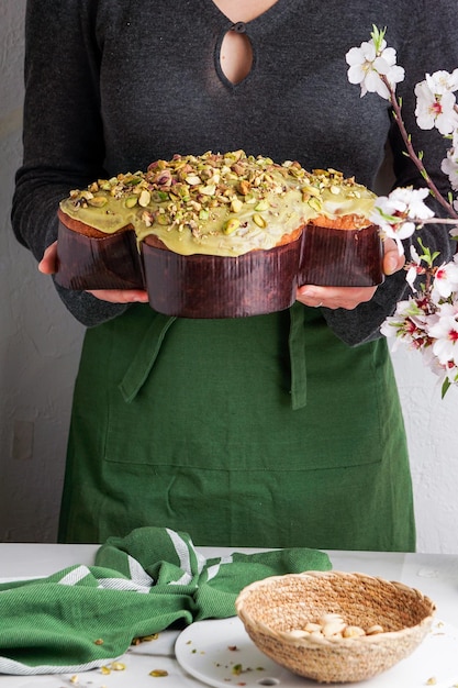 Colomba di Pasqua in the woman shef hands traditional italian easter dove cake with green pistachio glaze  fresh spring flowers pasqua cake