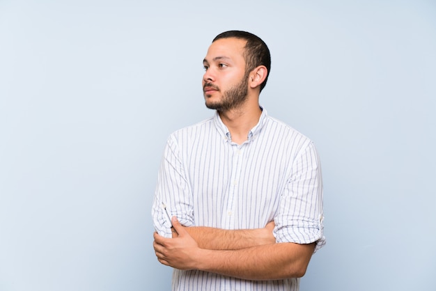 Colombian man over isolated blue wall portrait