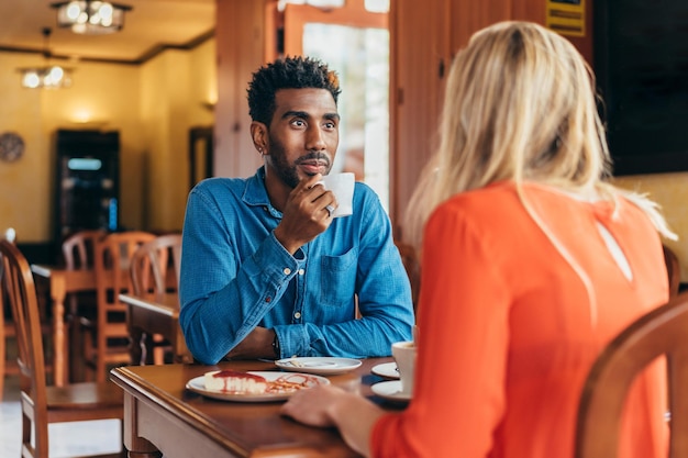 Colombian man listens attentively to a white woman while drinking coffee in a restaurant