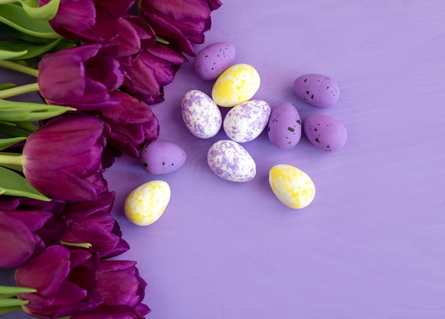 Color egg easter and purple tulips flowers on purple background .