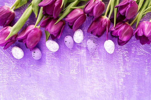 Color egg easter and purple tulips flowers on purple background .