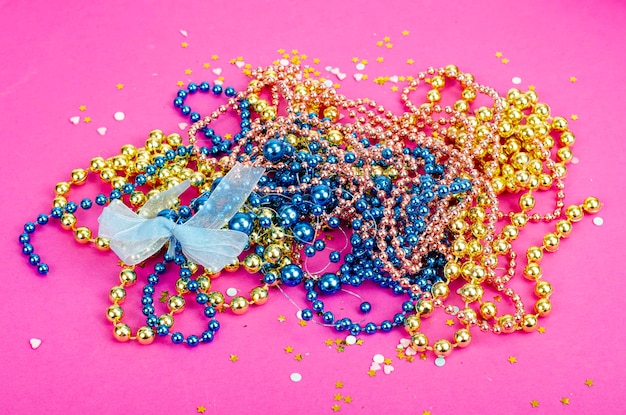 Color mardi gras beads, masks on bright background. Studio Photo