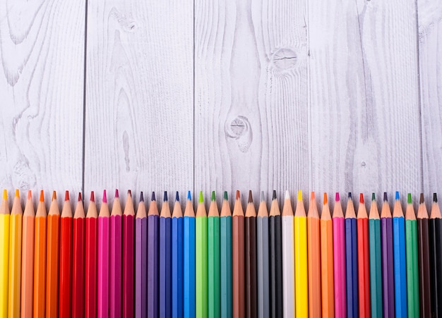 Color pencils in the background in white and gray wood, close up.