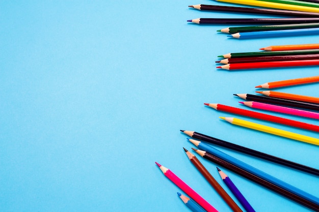 Color pencils scattered on a blue background