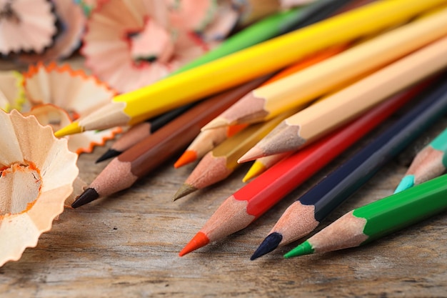 Color pencils and shavings on wooden table closeup