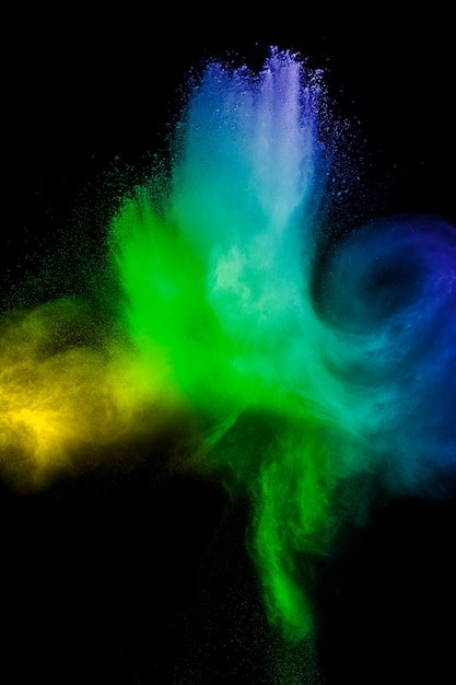 Color powder explosion cloud on black background. Freeze motion of color dust  particles splashing.