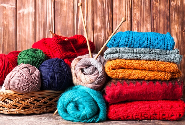 Color threads, knitting needles and clothes on the wooden table