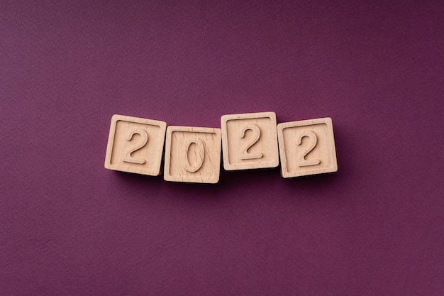 Color trends 2022 flat lay top view The inscription is made of ecofriendly wooden cubes The text is the color of the season on a burgundy background Bright concept of trends 2022