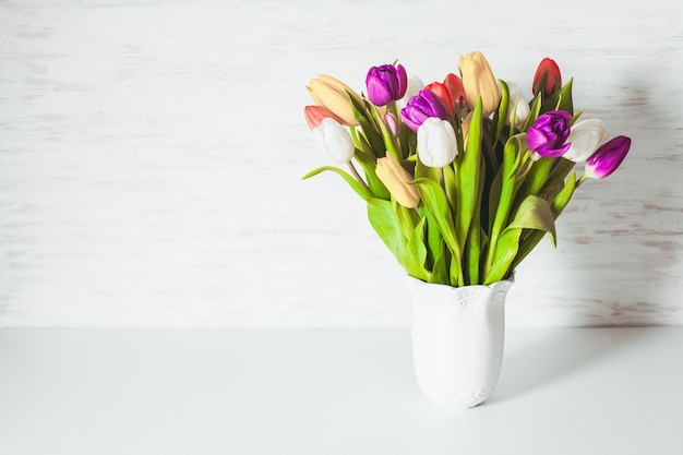 Color tulips in a white vase. Spring concept with copy space