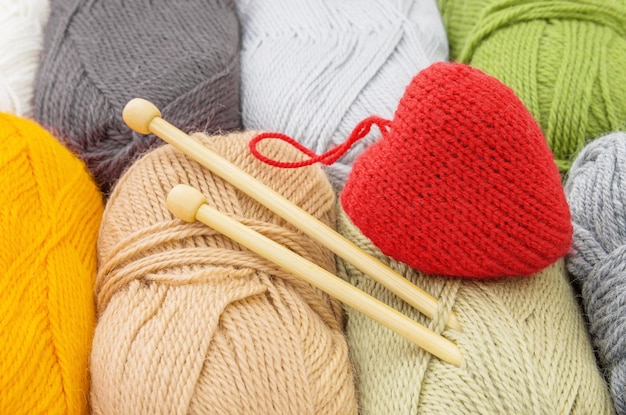 Color yarn skeins knitting needles and red heart close up The concept of knitting and loveValentines day