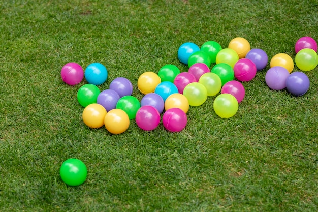 Colored balls for children to play thrown on the grass of the garden