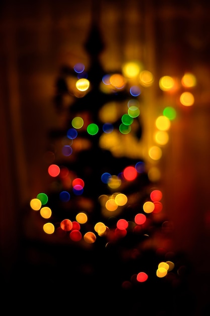 A colored bokeh in the background blurs a Christmas tree