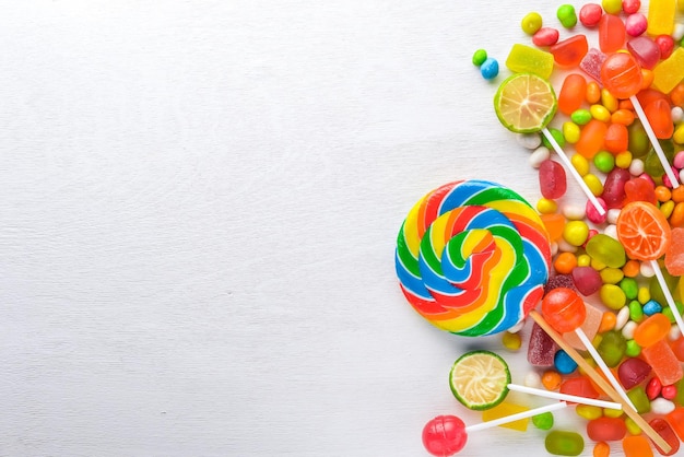 Colored candies sweets and lollipops On a white wooden background Top view Free space