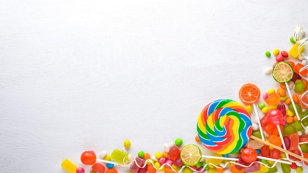 Colored candies sweets and lollipops On a white wooden background Top view Free space