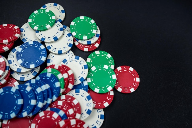 Colored casino poker chips scattered on a black table