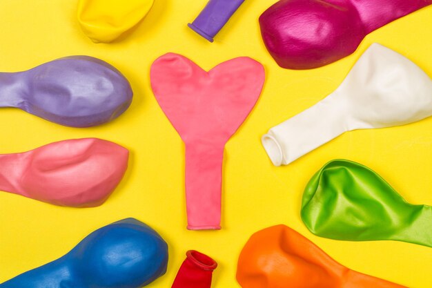 Colored deflated balloons on a yellow background