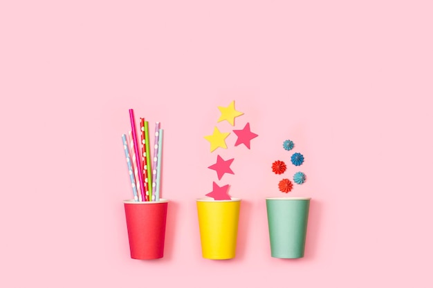 Colored drinking straws paper stars and meringues in colored paper glass on a pink background