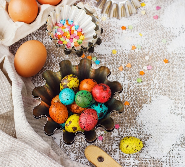 Colored easter eggs and baking molds on a light canvas background