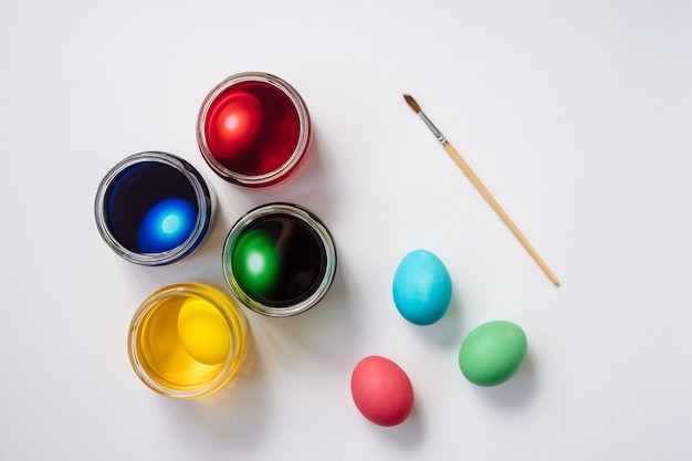 Colored easter eggs and egg dyeing set on white background.