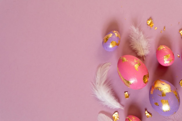 Colored Easter eggs and feathers on the violet background copy space