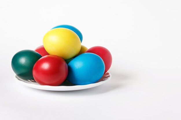 Colored easter eggs in white plate on white