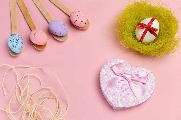 Colored Easter eggs on wooden spoons with a nest and a gift box