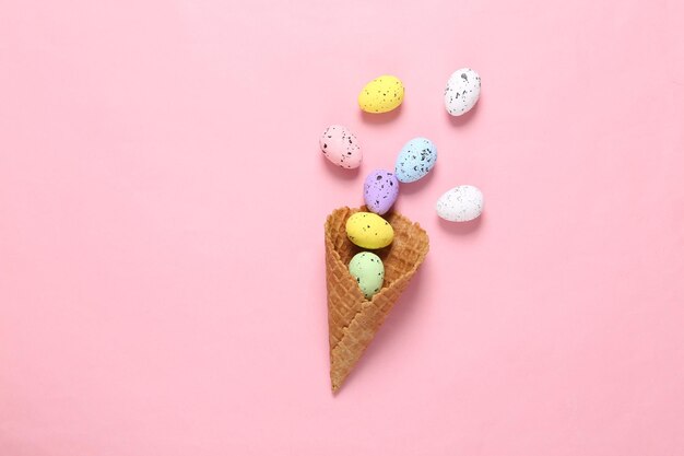 Colored eggs in waffle cone on pink blue background Creative Easter layout