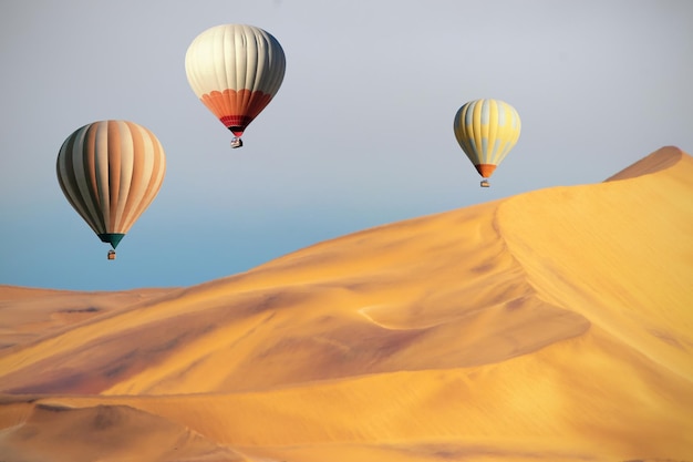 Colored hot air balloons flying over the sand dunes at sunset. Africa, Namibia. Beauty world.