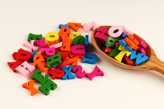 Colored letters in a spoon on a white surface as a symbol of knowledge and learning