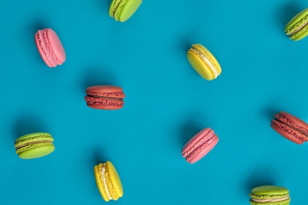 Colored macaron or macaroon sweet meringuebased confection on blue background Closeup copy space