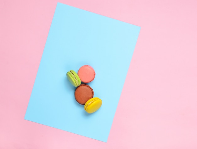 Colored macaroons cookies on a pink pastel blue background. Top view. Minimalism
