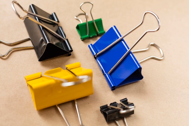 Colored paper clips on a brown table. Close-up. Background, craft paper