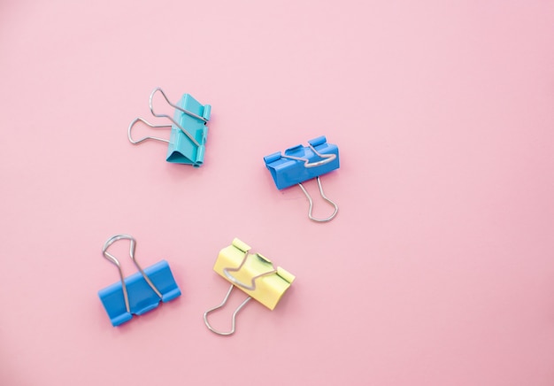 Colored paper clips on a pink background. Office stationary 