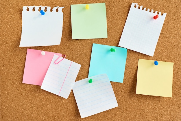 Colored paper stickers on a cork board background