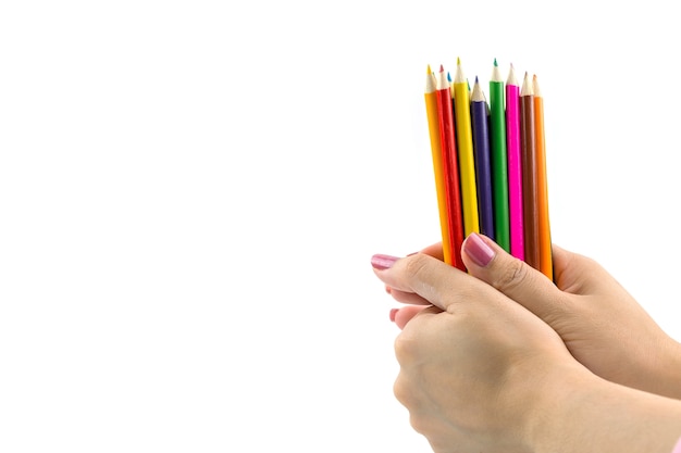 Colored pencils in female hand on white background