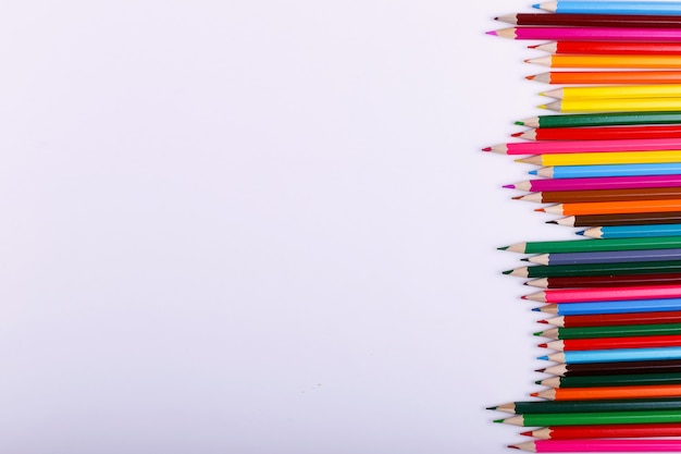 Colored pencils lie in a row on white