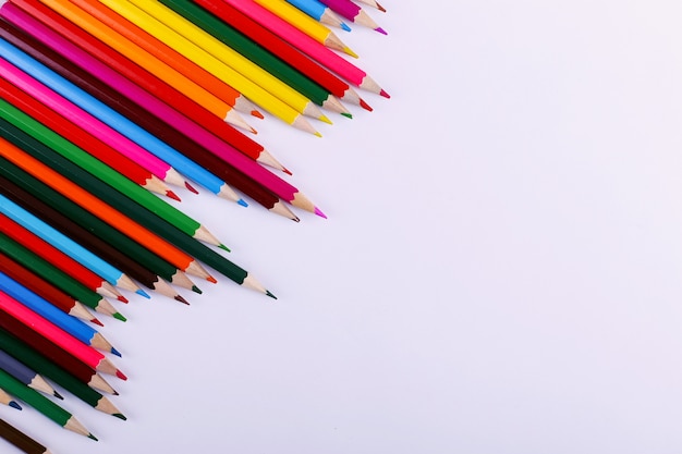 Colored pencils lie in a row on white