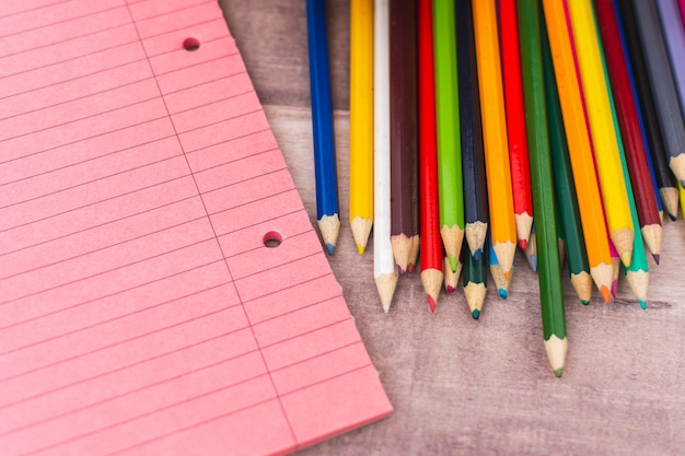 Colored pencils next to notebooks on a desk