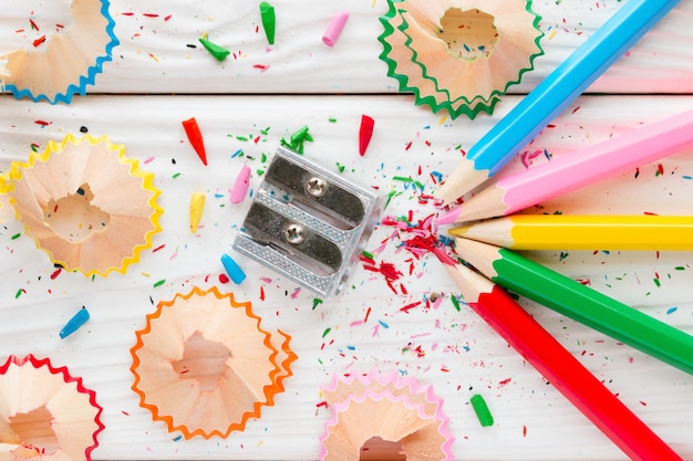 Colored pencils and pencil sharpener on a white wooden background