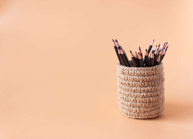 Colored pencils in a wicker basket made of jute