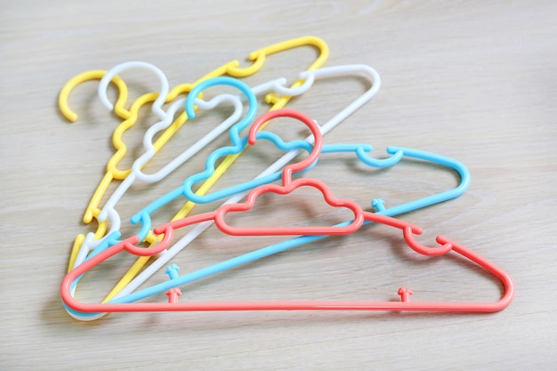 Colored plastic Clothes Hangers on wooden background