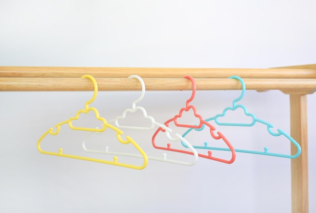 Colored plastic Clothes Hangers on wooden clothes line against white background