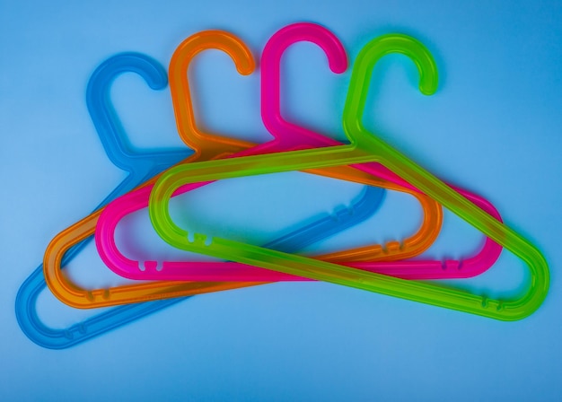 Colored plastic hangers on blue background Storage and sales concept