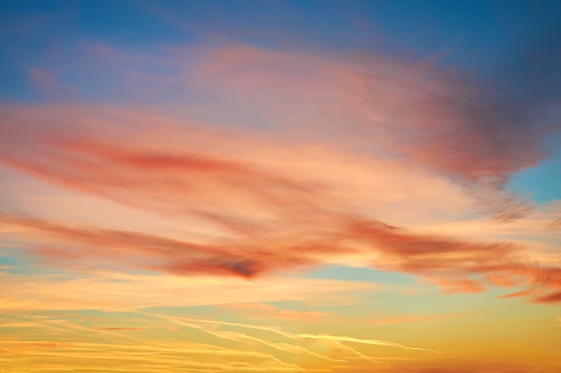 Colored porous clouds at sunset against blue sky.                  